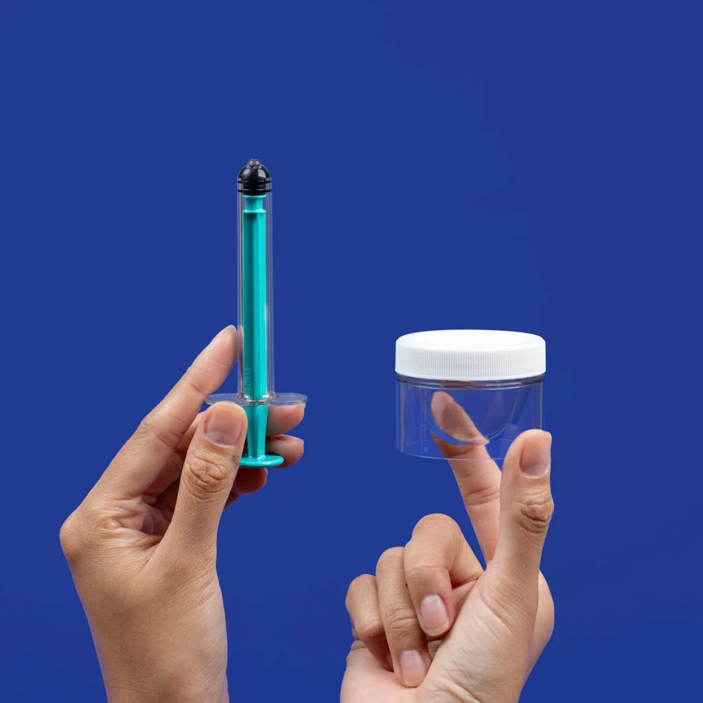 home insemination kit components: a syringe and a collection container against a blue background.