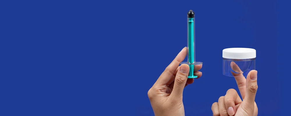 Hands holding a syringe and a small container against a blue background.