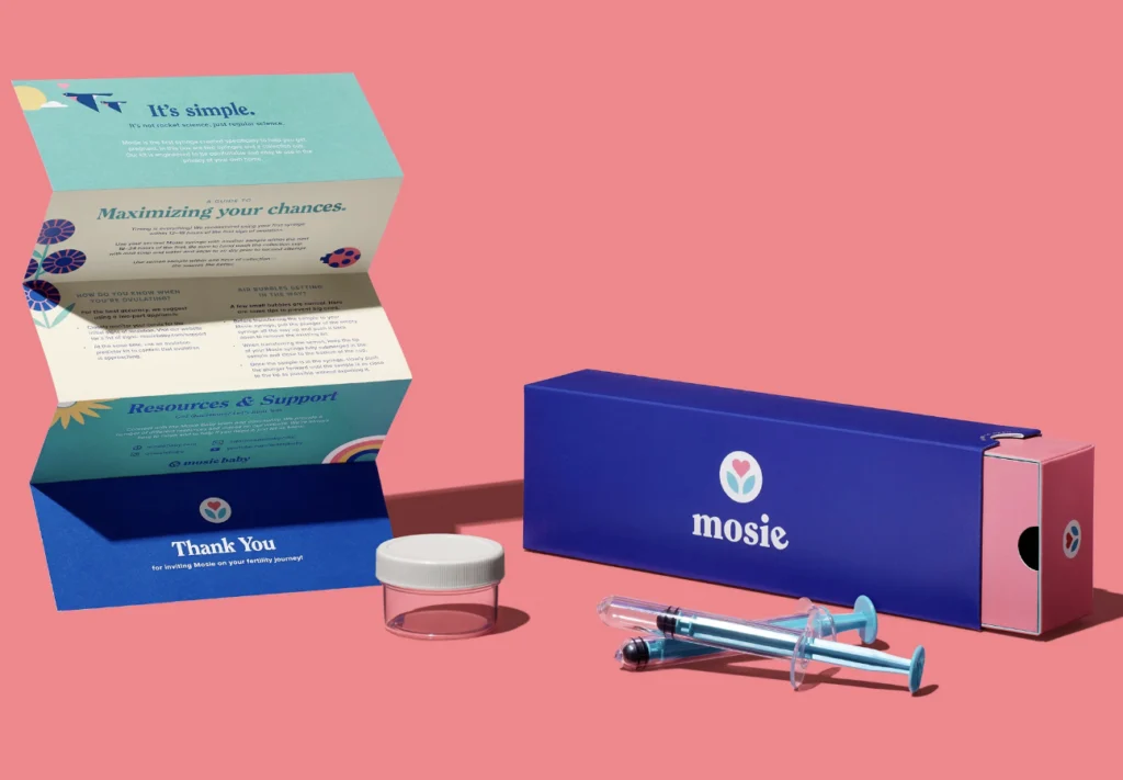 blue box with "mosie" logo, syringes, and informational pamphlet on a pink background