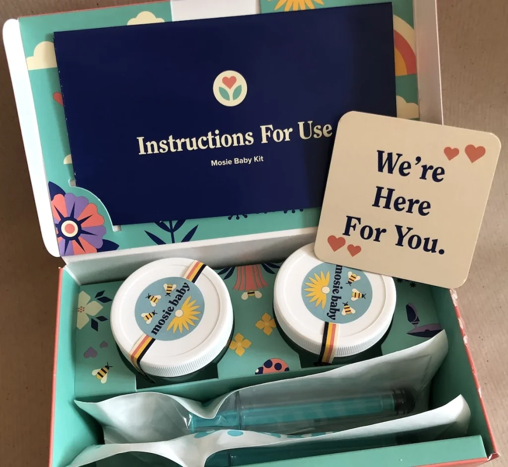Mosie Baby kit with two jars, a syringe, and a supportive message card inside a colorful box.