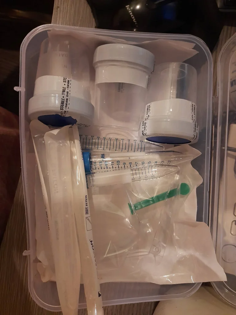various medical supplies and containers organized in a clear plastic box on a wooden surface